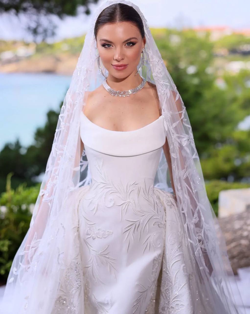 Maya Reaidy captivated the world on her wedding day in Greece, making a grand entrance at Athens’ Olympic Stadium in a breathtaking custom bridal gown by GEORGES HOBEIKA. The former Miss Lebanon’s dress embodied the Maison’s renowned craftsmanship, merging a sculptural elegance with a dreamlike, enchanting aesthetic.Drawing inspiration from 18th-century fashion, the gown’s majestic silhouette harmonized with the bride’s personality and the grandeur of the surroundings. The meticulous artisanship brought the luxurious fabrics to life, with a skillful interplay of contrasts and volumes.The design featured a crystal-studded tulle overskirt that added an aura of mystery and light to the mermaid-style dress, while a strapless bodice in double silk crepe was delicately embroidered with matte silk threads. The intricate silk thread embroidery continued onto the sparkling veil, enhancing the gown’s ethereal allure.Crafted by eleven skilled artisans, the gown required 714 hours of meticulous work, resulting in a truly unique and mesmerizing creation fit for a fairytale wedding!Congratulations@mayareaidy@georgeshobeika @jadhobeika@patricksawaya#mayareaidy #bridal #georgeshobeika #fashioninspo