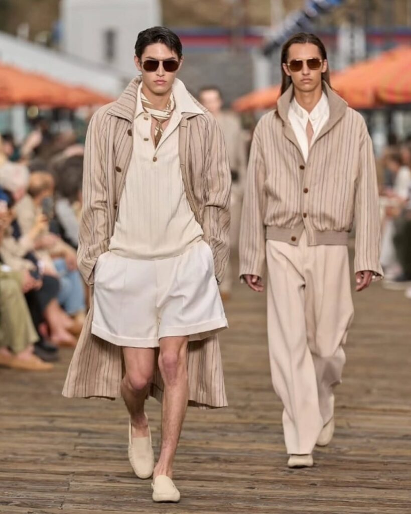 From Malibu Pier to the spirit of an endless Italian summer, Zegna’s latest presentation transformed La Villeggiatura into a lesson in effortless elegance. Inspired by the Italian tradition of relocating life—not simply escaping it—for the season, Alessandro Sartori delivered a wardrobe where ease and sophistication coexist seamlessly. Vibrant shades of orange, green, and blue punctuated relaxed tailoring, lightweight layers, and textured fabrics, creating a vision of summer that felt both refined and lived-in. Less vacation dressing, more a complete seasonal wardrobe designed for a life well-traveled.