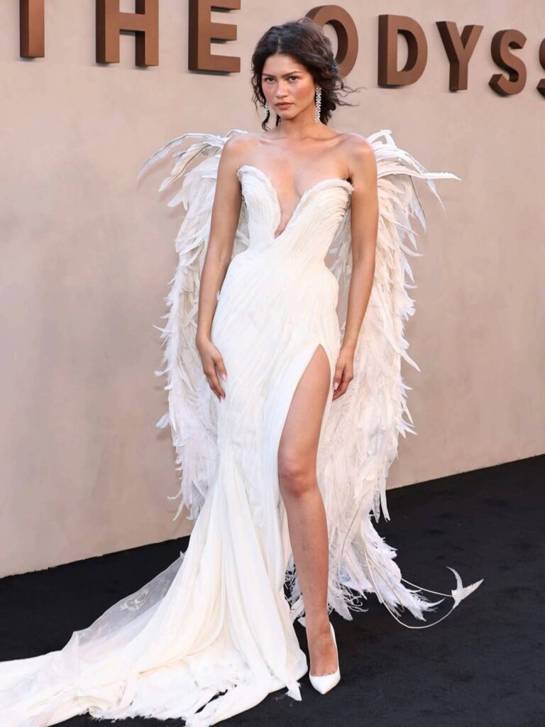 Zendaya delivers one final fashion triumph before The Odyssey hits the big screen. Stepping onto the New York City premiere red carpet, the actress embraced her role as the Greek goddess Athena in a breathtaking winged, draped white gown by Paris-based label Matières Fécales. Ethereal yet strikingly modern, the look blurred the line between mythology and avant-garde couture—proving once again that when it comes to cinematic dressing, Zendaya rarely misses.